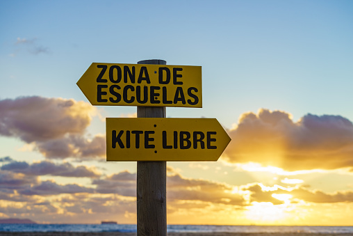 Sign in spanish at sunset beach navigate lesson and kitesurfing. Sports activity.